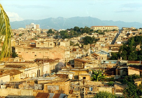 "Welch ein Chaos an Dächern lag da unter, welch eine gewaltige Senke an Stadt lag da vor ihm, begrenzt von einem Hügelkamm, der unterm schrägen Nachmittagslicht in allen Ocker-, Braun- und Grüntönen aufschimmerte, dahinter, flau, die Silhouette der Berge ...": Santiago de Cuba vor der Gran Piedra